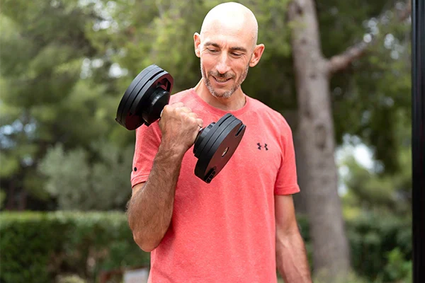 Guillaume réalisant un curl biceps avec haltères réglables Fitnesstorm, illustrant un exercice de musculation des bras.